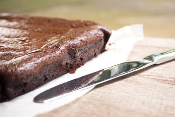 Closeup side of brownie. Knife nearly and shadow light. Dessert background. 