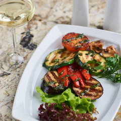 Grilled vegetables served on white plate. Eggplant, tomato, paprika and Zucchini slices.