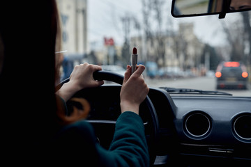 young woman driving a car paints lips