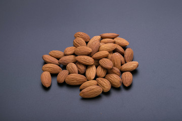 Almonds in wooden bowl on a black background