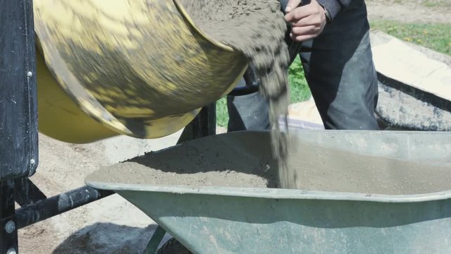 Industrial cement mixer machine at construction site. Concrete pouring.Construction worker mixing mortar. Pouring concrete mix from cement mixer.
