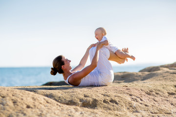 A mother and a son are doing yoga exercises at the seashore of Mediterranean sea