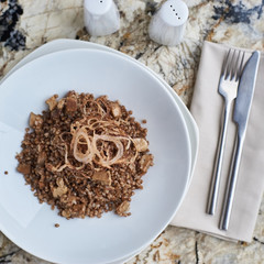 Buckwheat with porcini mushrooms served on white plate on marble table