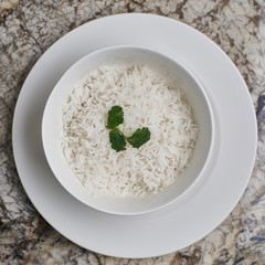 White bowl with white boiled rice on marble table