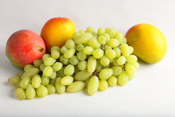 Green grapes and mangoes on white background.