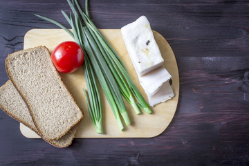 Lard (Salo), green onions, bread, red tomato on a wooden background.