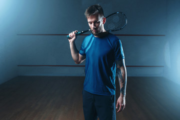 Squash player with racket, indoor training court