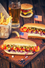 American hot dog with pickles,onions, ketchup, mustard and french fries at a Picnic for 4th of July 