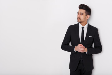 Young businessman in black suit on a white background. Confident man looking away from the camera.