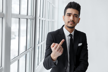 Young attractive man in a black suit showing gesture fuck