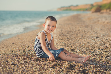 The boy running on a beautiful beach. The boy walking on a beautiful beach. Sea foam on the sand....