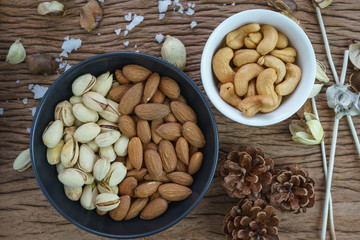 appetizer roasted healthy delicious salt pistachios, cashew nuts and almonds food in black bowl on wooden table background