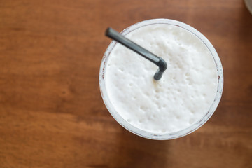 Milk froth in a cup on wood table, top view