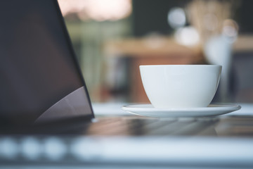Hot coffee with laptop on table in the modern office