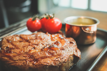 Close up of beefsteak on the tray in the restaurant, vintage tone.