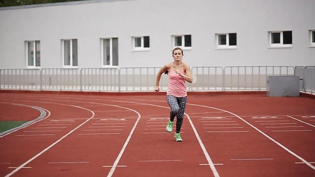 Track runner athlete woman warming up before running at a stadium, slow motion