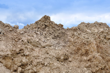 Yellow sand and gravel mountain close up on a background of blue sky.