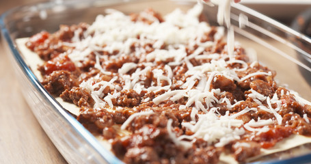 preparing traditional italian lasagna adding cheese