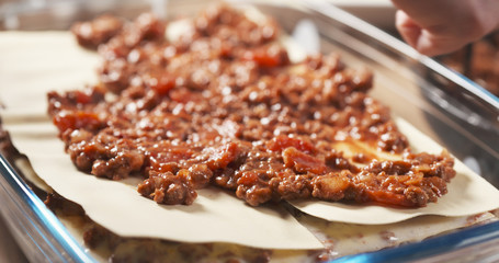 preparing traditional italian lasagna adding bolognese sauce