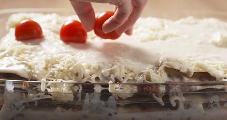 preparing traditional italian lasagna decorating with cherry tomatoes