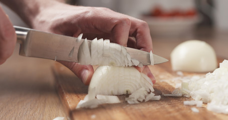 man cutting white onion with knife - obrazy, fototapety, plakaty
