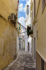 Small alleyway decorated with colorful buntings in the historic center of Gallipoli, Puglia, Italy