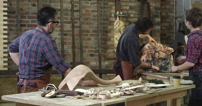 Wooden Furniture Restoration Workshop/An average day at a family woodworking shop. Young man polishes a cabrioli leg before finishing coating