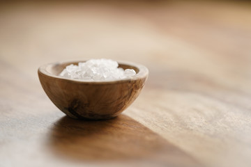 Fototapeta na wymiar coarse sea salt in wooden bowl on table