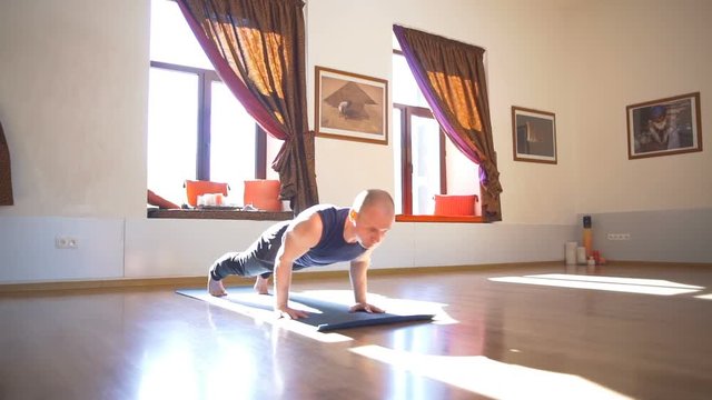 Man standing in the upward-facing dog pose in the room slow motion