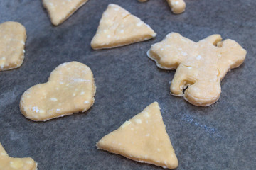 Cookie dough in different shapes lies on the baking sheet.