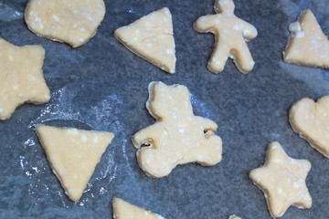 Cookie dough in different shapes lies on the baking sheet.