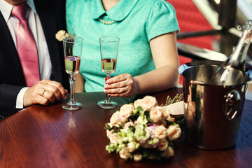 Womans and mans wedding hands with glasses.Happy newlyweds couple drink white wedding champagne wine.New family,husband and wife celebrate engagement