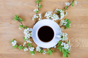 Cup of coffee and spring tree blossom on wooden background. Copy space. Top view.