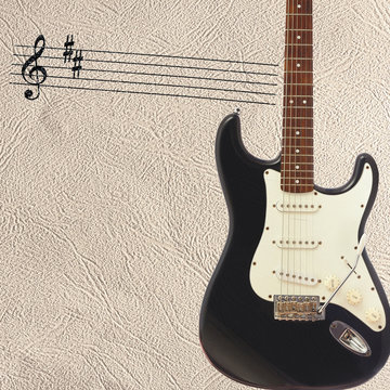 Notes and solid body classic electric guitar on the right side of the light skin background.
