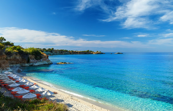 beach with white sand and clear blue water in beautiful Bay with sun beds and umbrellas, Crete, Greece © vladimircaribb