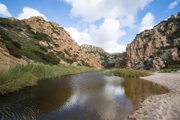 A beautiful natural river between the Italian mountains. River flowing into a beautiful beach in Sardinia.