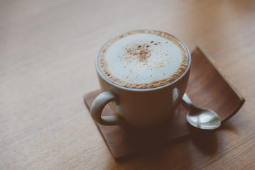 Hot coffee in white cup with brown sugar in glass jar Placed on the bar by the window in selective focus.