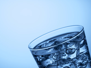 top of a glass of water with ice cubes on a light blue background