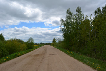 Fototapeta premium Beautiful countryside rural landscape: sandy road and dark clouds in the sky, nature 
