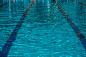 The surface of turquoise water in the pool as a background. Clean and bright water in swimming pool. Ripple water in swimming pool with sun reflections.