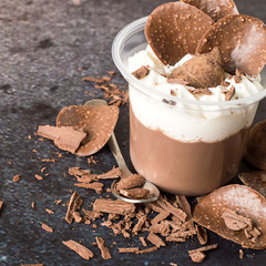  A delicate dessert. Pudding with whipped cream and pieces of chocolate on a dark blue background.