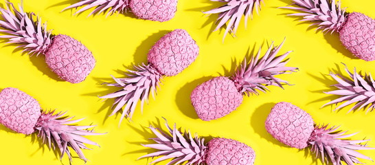 Pink painted pineapples on a vivid yellow background - obrazy, fototapety, plakaty
