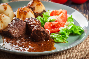 Pork meat stew served with potatoes and vegetable salad