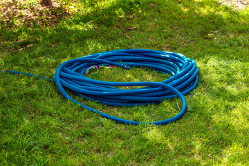 Equipment for watering. The hose is rolled onto a roll lying on the green grass. In summer heat plants need irrigation, watering. 