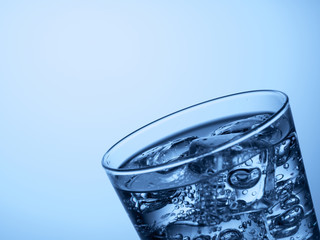top of a glass of water with ice cubes on a light blue background