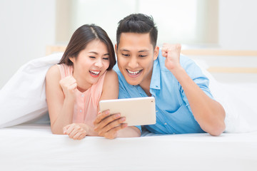 Asian family watching tablet in bedroom