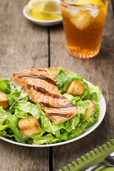 Salmon Caesar Salad with Iced Tea on Wood Table