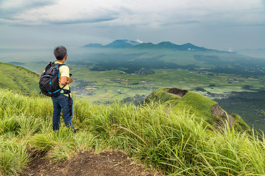 Hiker trekking to the hill top and watching mount Aso volcano in Kumamoto