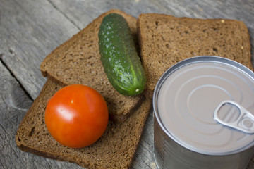 Closed canned food near sliced bread on wooden background