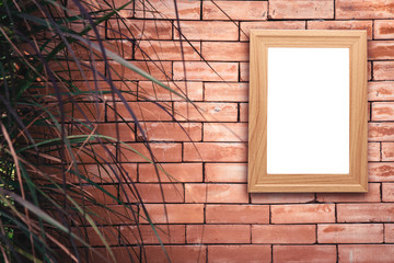 Mock up blank poster picture wooden frame on old brick wall in vintage tone with grass front ground.